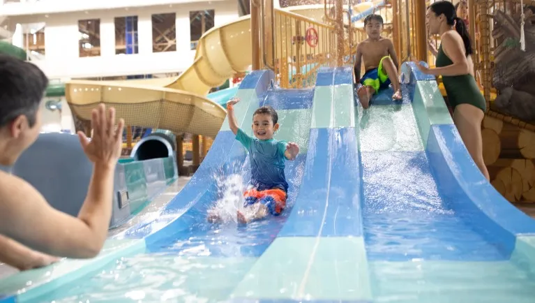 A small child floats down a water slide as the father holds him at a Great Wolf Lodge indoor water park.